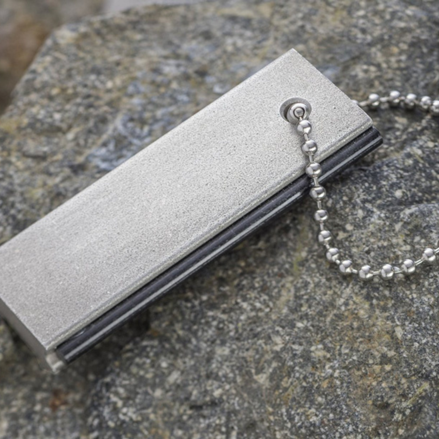 Silver flint and steel with chain on a textured stone surface