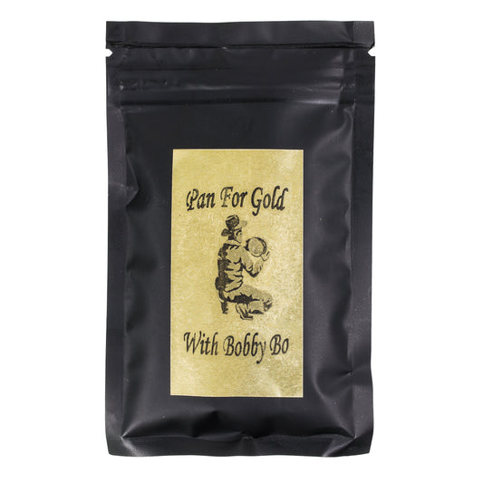 A sealed black paydirt bag with a gold label featuring text and an illustration of a person pan fishing for gold.