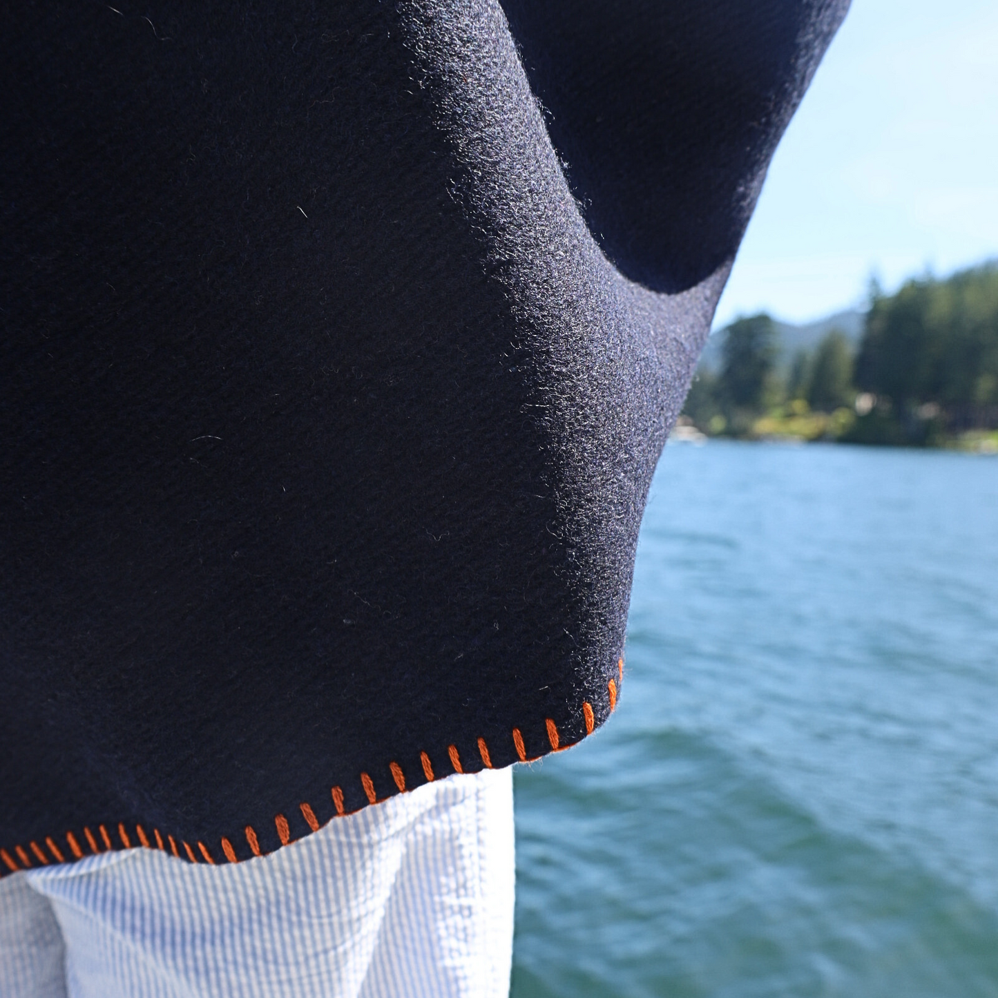 Close-up of a blanket with orange stitching against a blurred natural background