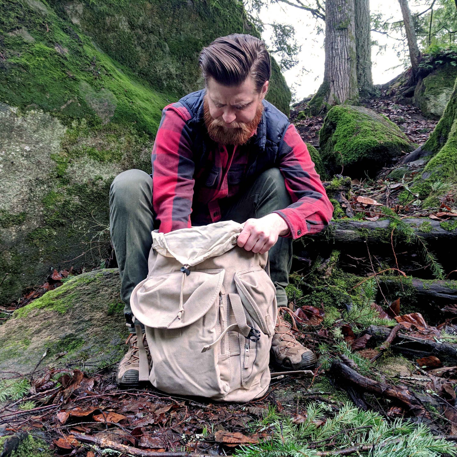 gold panning backpack with green gold pan in a forest river