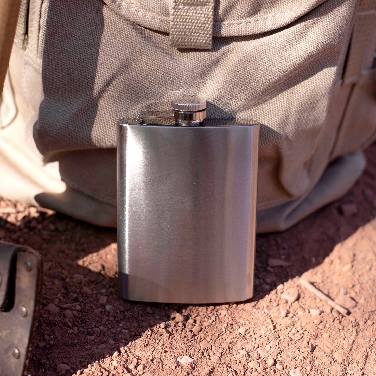 Stainless steel flask on a dirt ground.