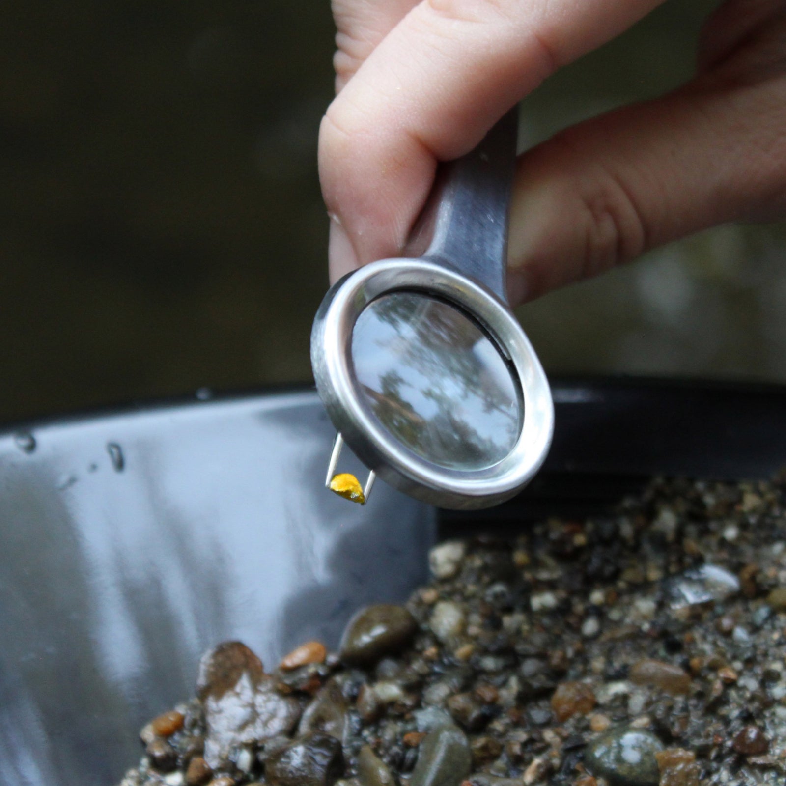 A set of gold panning accessories including a pair of magnifying tweezers and four glass collection vials with screw tops.