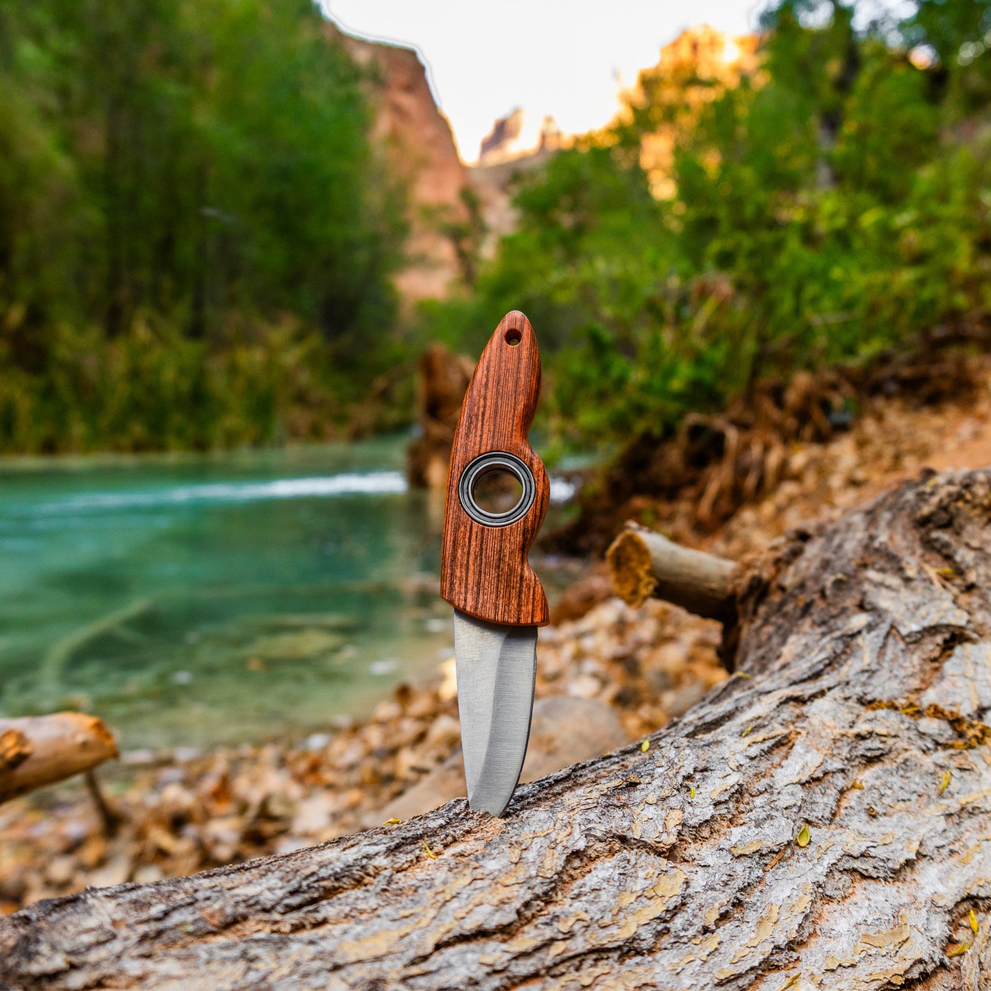 small blade trick knife with spinning wheel in a beautiful log and river