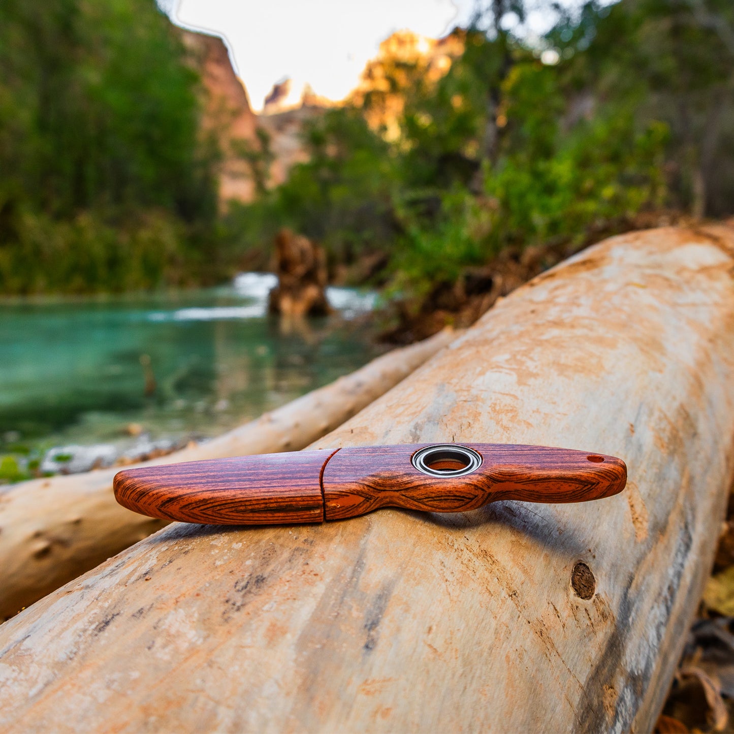 Spinning knife with sheath on a log by the river