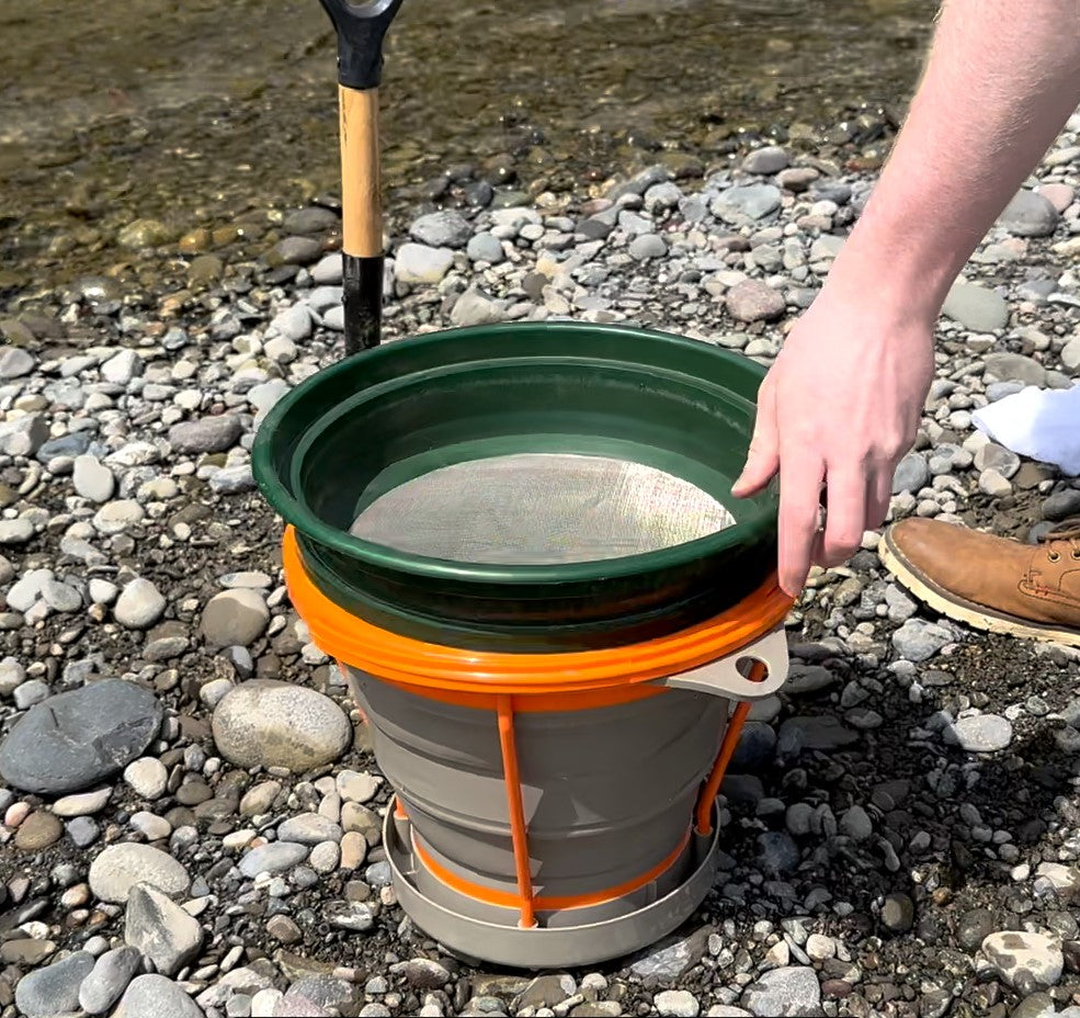Collapsible bucket rock classifier being used on a rocky surface