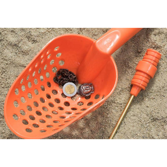 Orange plastic scoop with holes on beach sand