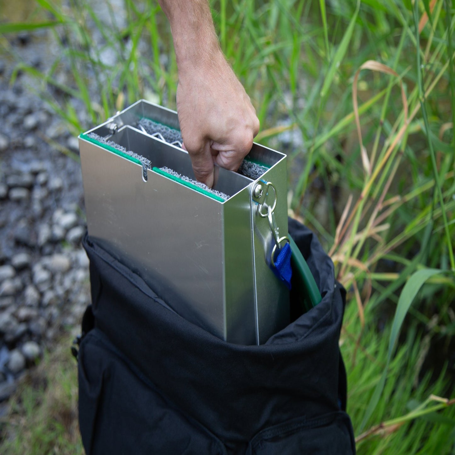 gold panning backpack with green gold pan in a forest river