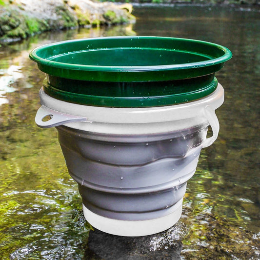 Collapsible green and gray water container on a natural background