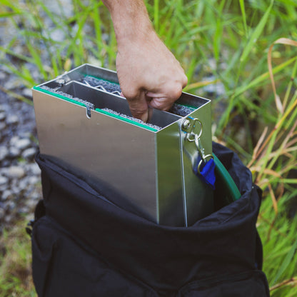 foldable sluice box being pulled out of a black backpack