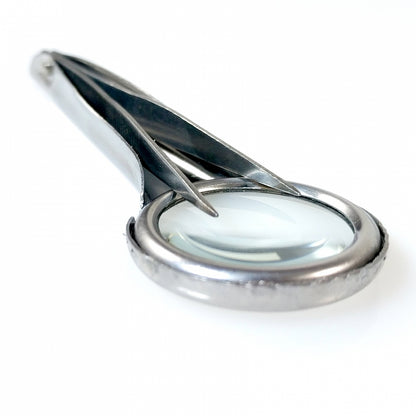 close up detail shot of tweezers magnifying glass