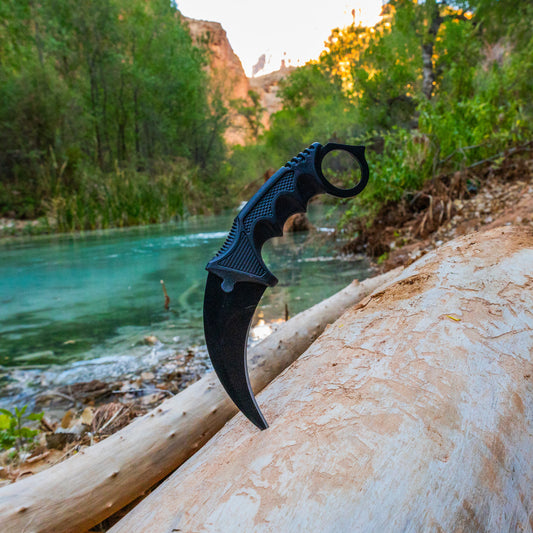 Karambit knife stuck in tree log for beautiful photo of knife by river in canyon